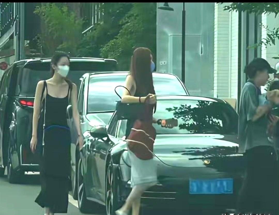 窦靖童怀里抱着爱犬，旁边走着穿黑色吊带长裙的李嫣。镜头一转，宋妍霏也在。她穿着黑无袖上衣搭白裙子，跟