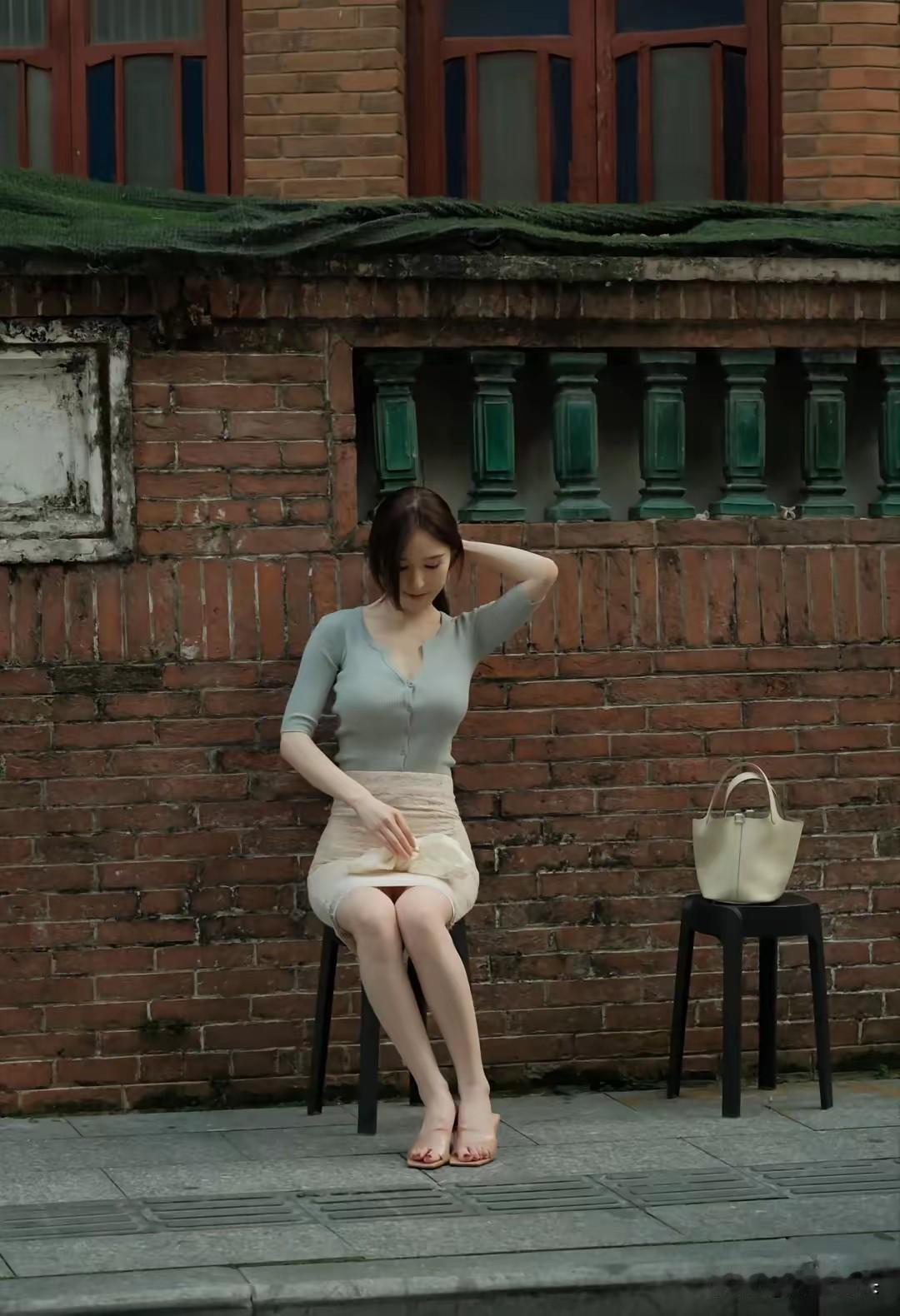 复古红砖墙前，优雅女子轻抚发丝，静享悠闲时光。