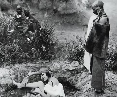 1923年，非洲肯尼亚，一名白人女子在郊外水坑里洗澡。她皮肤白皙光滑，用刷子悠闲
