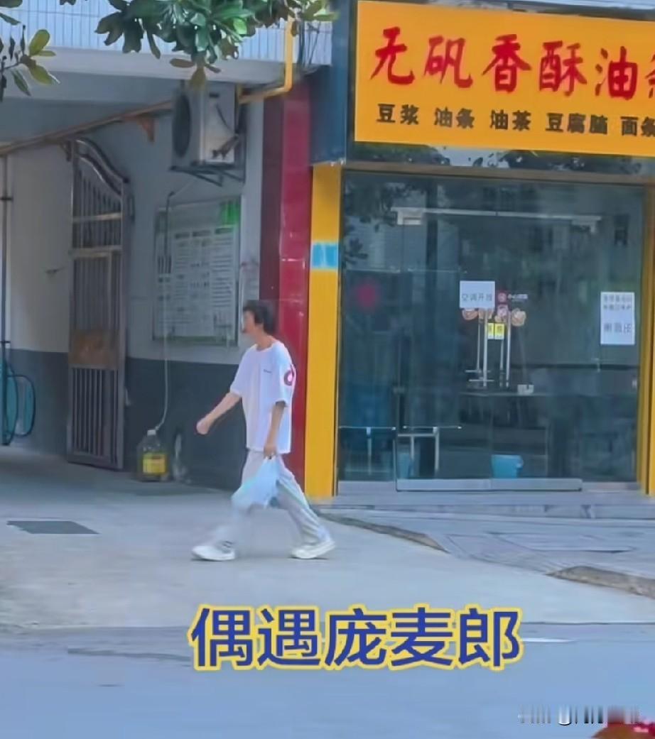 汉中街头偶遇国际巨星庞麦郎。他一身白T恤白裤子白运动鞋，这次没戴帽子、墨镜，手里