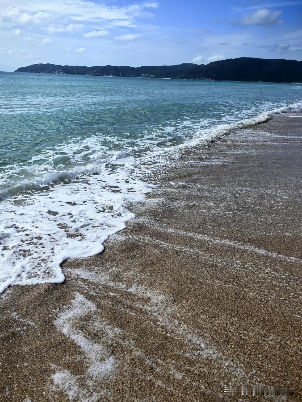 这儿的海水很蓝，但是浪有点大。今天天气有点大，沿着海滩走过去，时不时的一个大浪