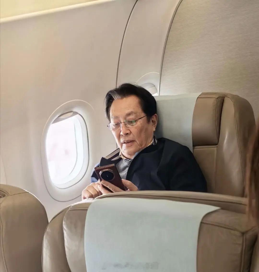 73岁唐国强在飞机上被偶遇，他坐在头等舱，翘着二郎腿看报纸，一副领导出行的派头，