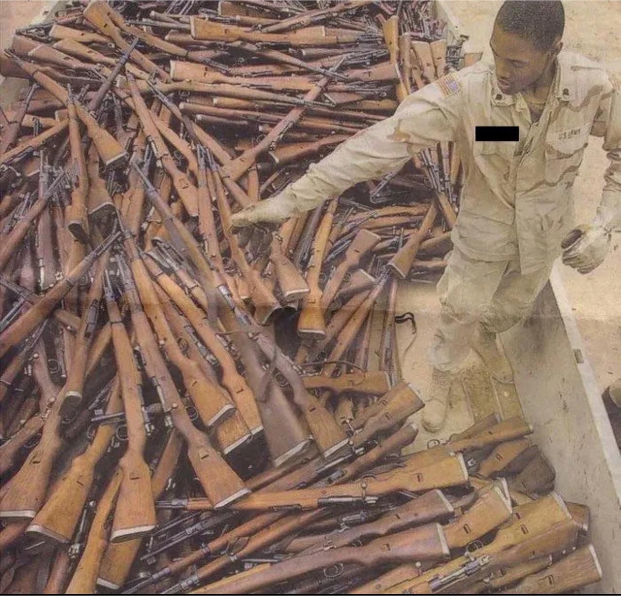 一名美国陆军士兵站在一堆南斯拉夫扎斯塔瓦M48栓动步枪旁边，这些步枪属于萨达姆时