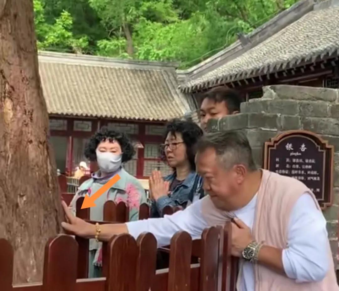 香港曾志伟右手摸树后双手抱拳祈福。