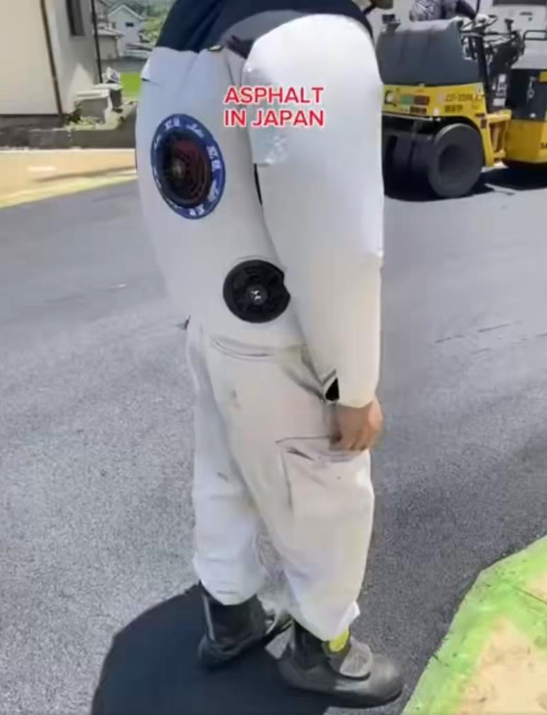 日本道路和建筑工人在夏季高温下铺设沥青时穿着带有风扇的背心，内置风扇在衣服内循环