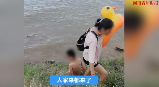 2025年7月江西南昌，一女子带着自己的儿子跑到河边，坚持要坐在游泳圈上下河玩耍