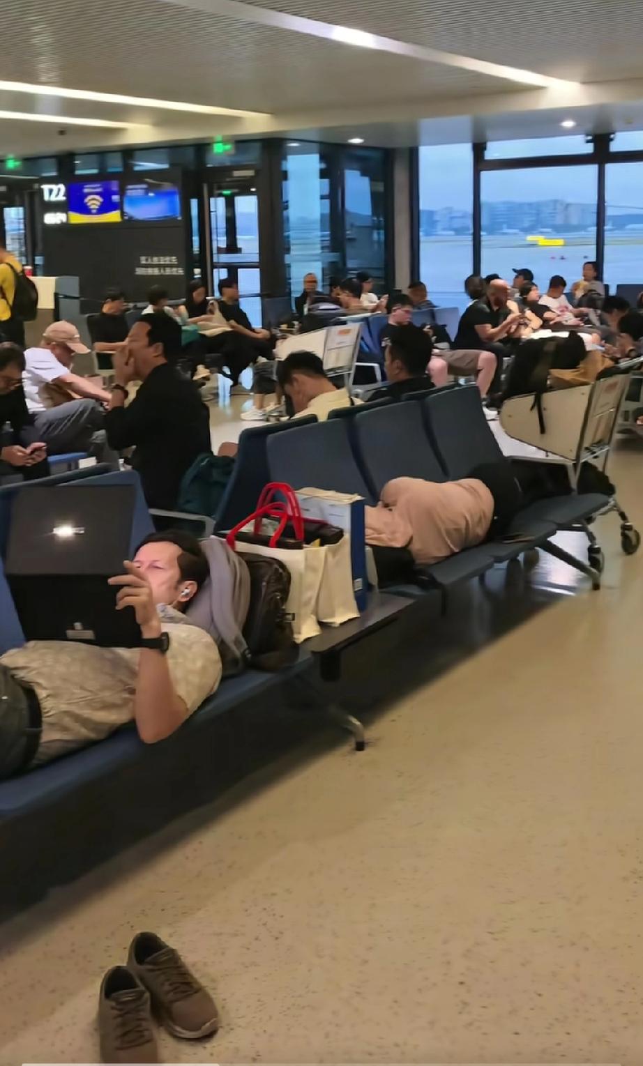 上海虹桥国际机场，两外国人脱鞋躺在座椅上霸占了六个座位，一个在睡觉，一个在专心的
