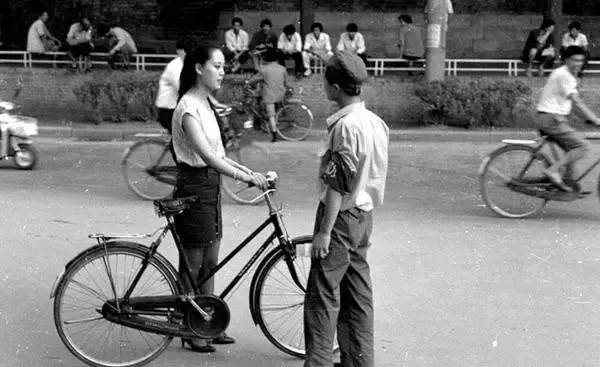 80年代，一位男士穿着制服，戴着帽子，胳膊上佩戴红袖章，上面写着“勤“字，在街头