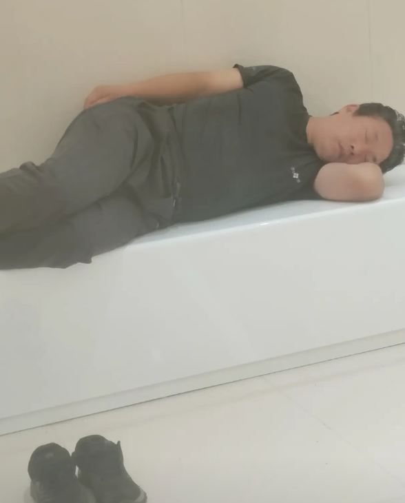 一个50岁左右的男人在一家商场的角落里这么躺着睡觉，从商场上午10点开门一直躺到