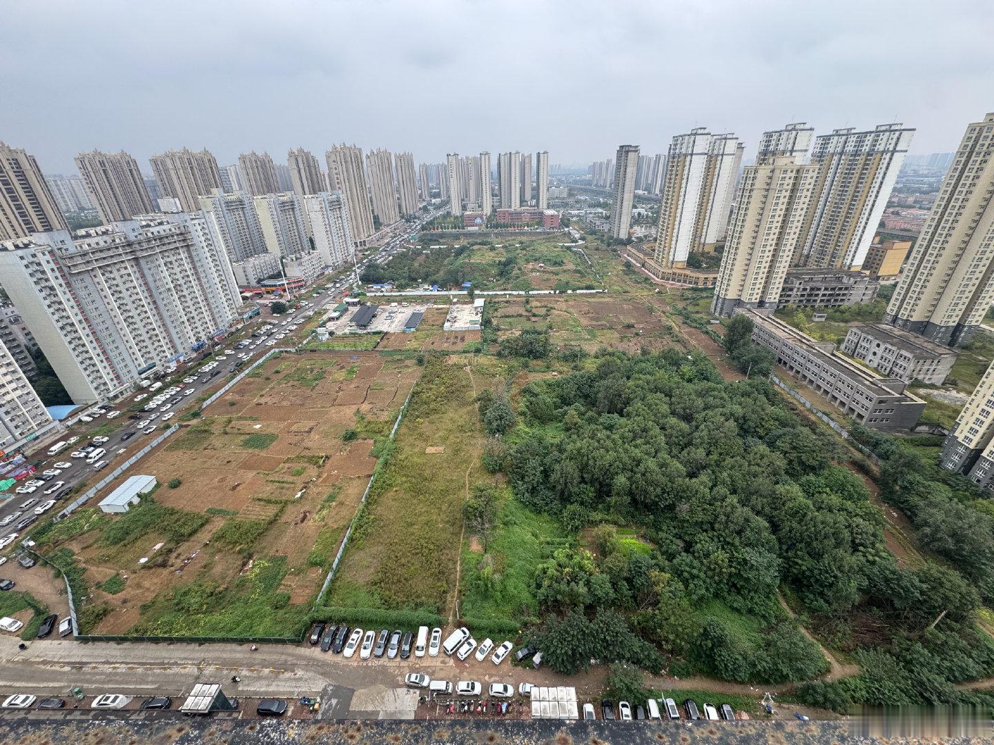 郑州三环外四环内，居然还有这样的地方，右侧是烂尾楼，中间是菜地及林地，左侧是居民区……​