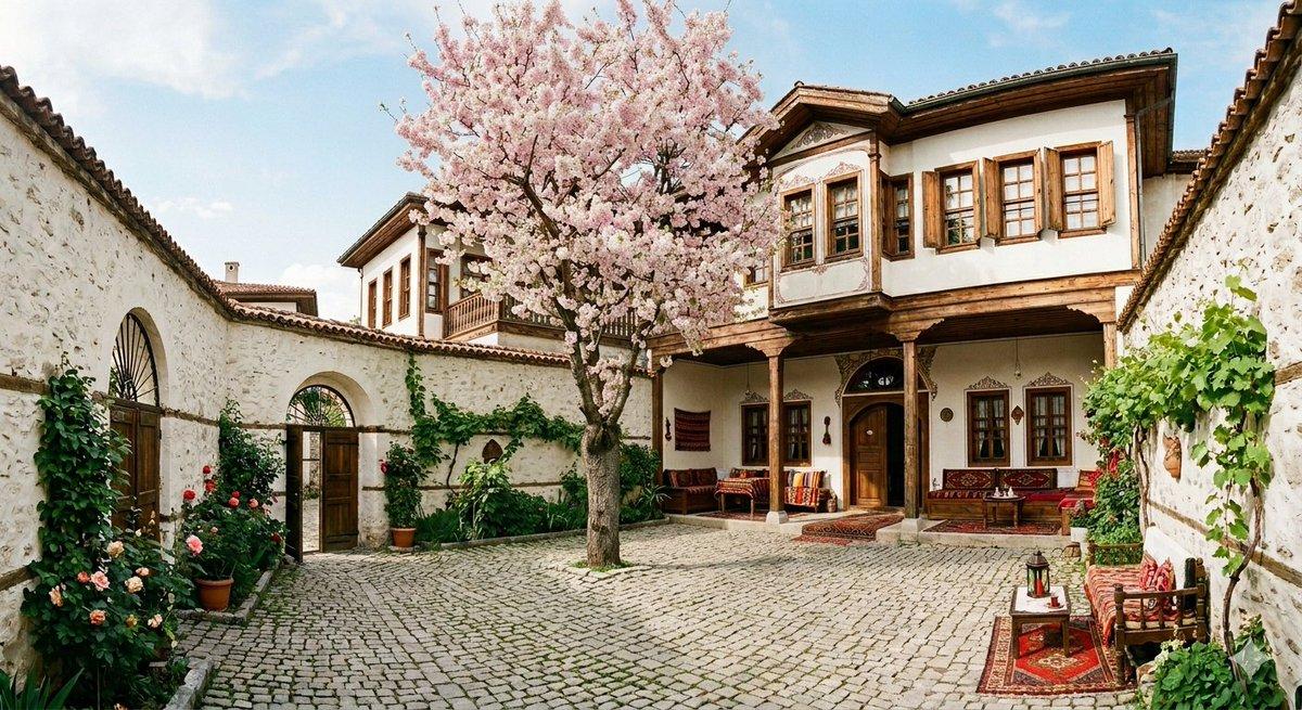 一座典型的奥斯曼时期土耳其传统住宅，庭院中栽种着一棵盛开的樱花树，四周是石砌围墙