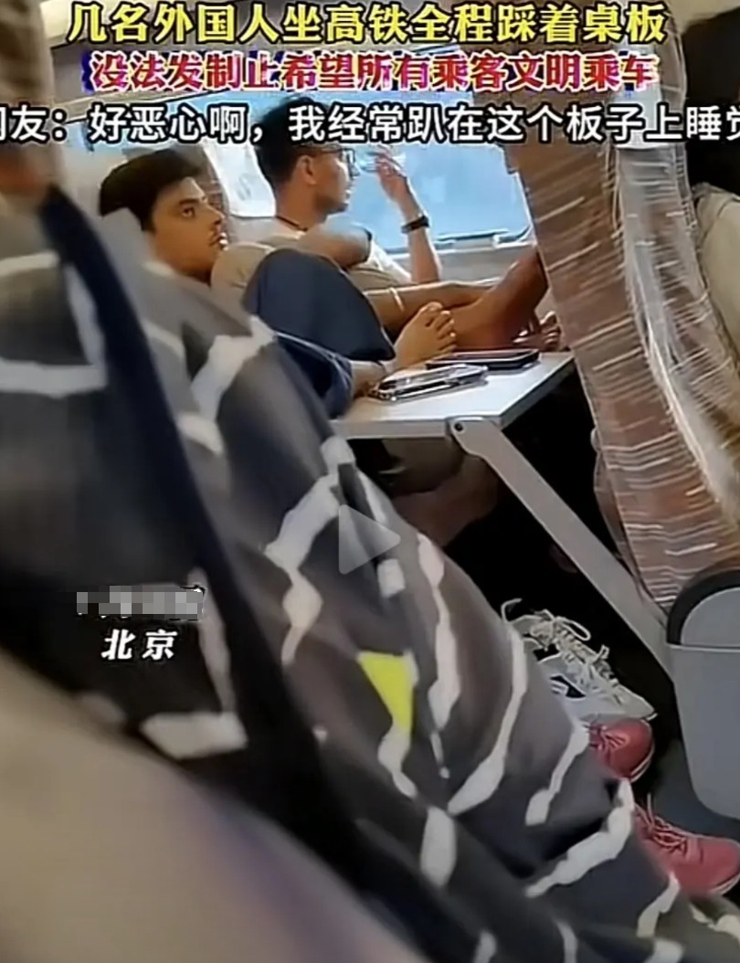 今天看到这真让人气愤！几个外国人在中国做高铁，把脚踩在桌板上了，居然没有人制止
