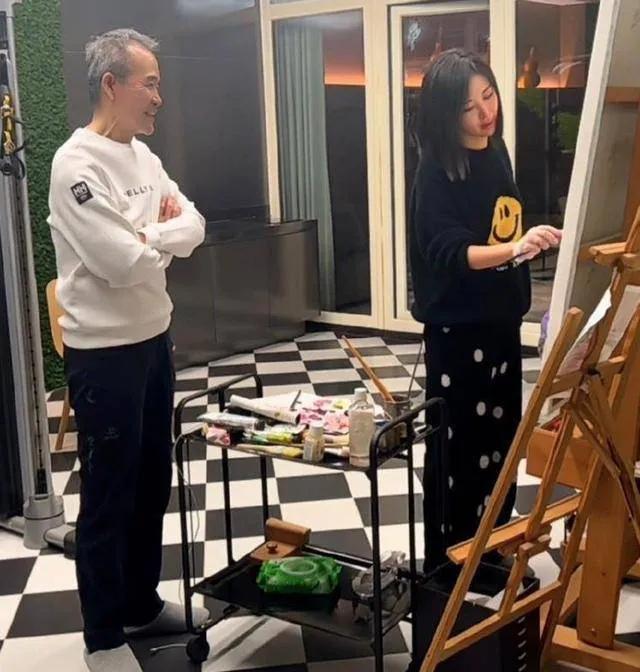 当小娇妻田朴珺在家作画时，王石则静静地在一旁观看。身板笔直的他双手交握，满脸笑容