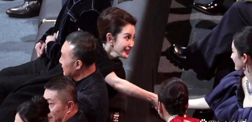 辛芷蕾先起身，腰折成90°，像给李冰冰递上一把隐形梯子；杨幂屁股黏椅，只把手腕抬