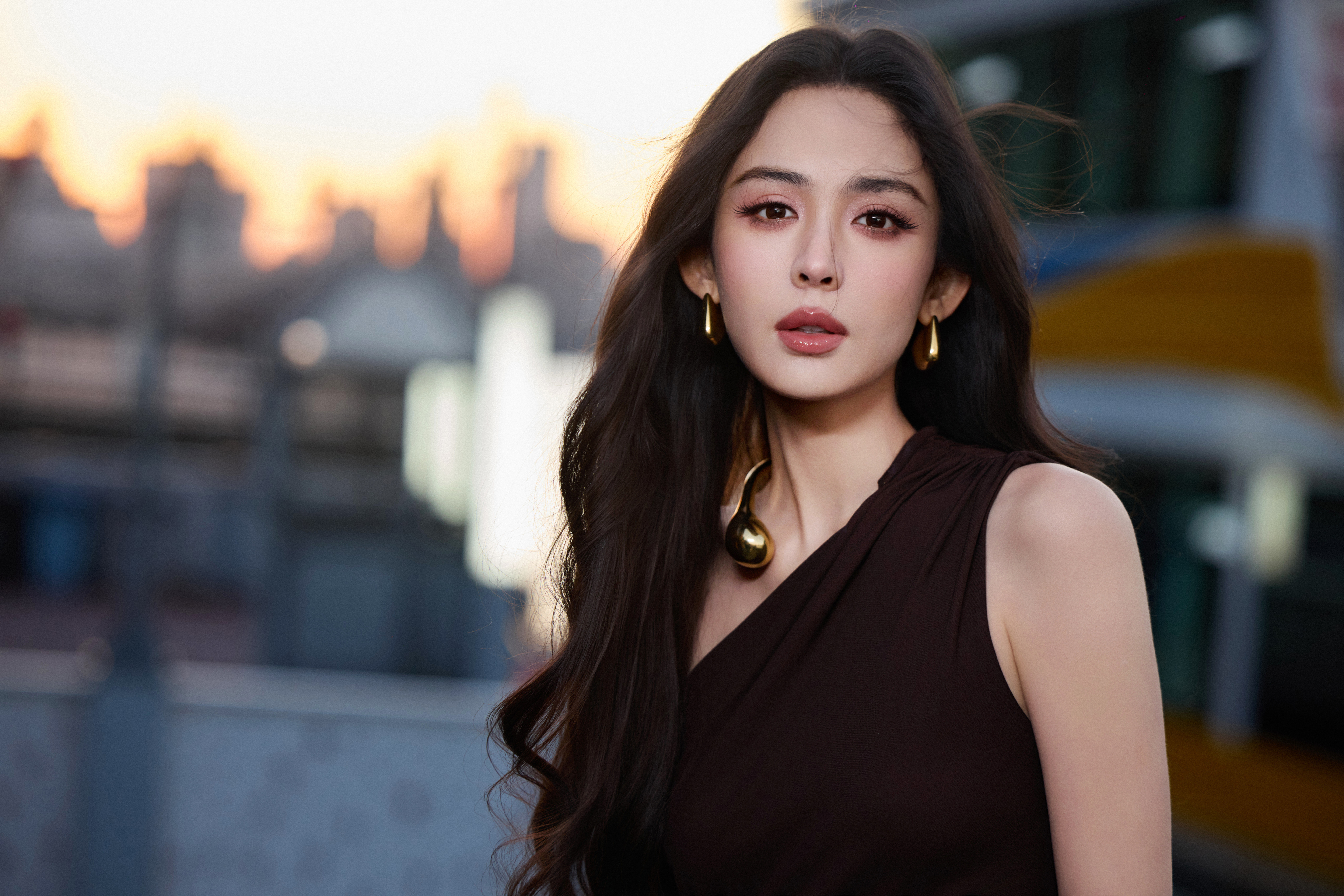 古力娜扎深棕裙装勾勒出从容的轮廓，暮色里的她自带松弛而舒展的高级感。