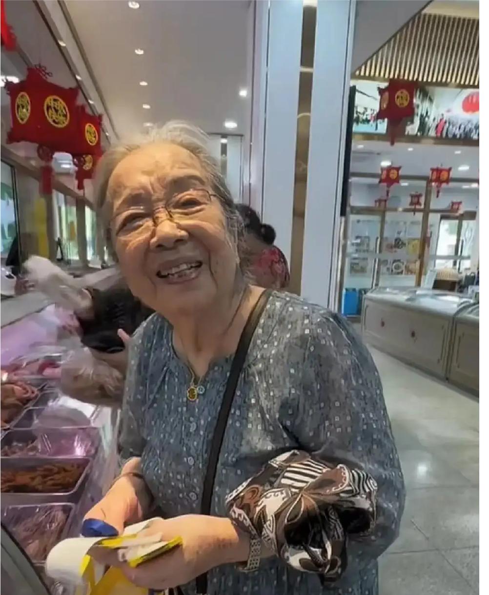 90岁李明启在北京菜场给重孙买好吃的，被网友偶遇，她穿着灰色长裙，挎着斜挎包，脚