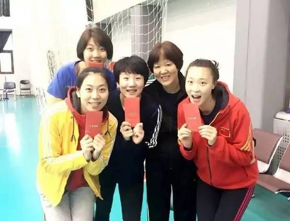 手捧红包的女排姑娘与郎导的合照画面中的袁心玥柳眉杏眼，卧蚕精致；穿黄色运动服