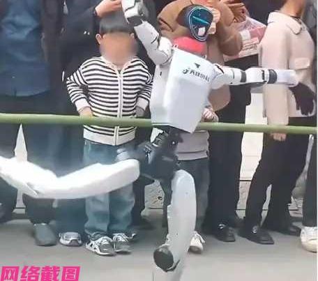 陕西有家商场在门口举办机器人表演，此刻围了一群人，其中有个小男孩挤在前面，由于机