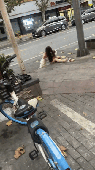 寒冷的清晨街头。网友拍到一名衣衫不整的年轻醉酒女孩坐在马路边上。在现场还有一