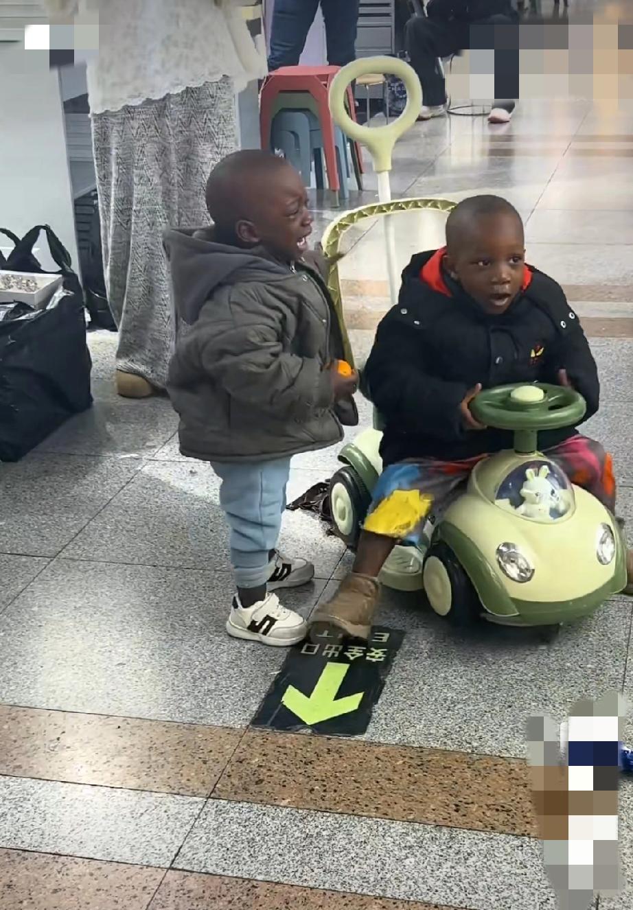 浙江，两黑人孩子在档口玩耍打闹，逗得旁边的档口老板大笑不止。也不知道这是谁家的黑