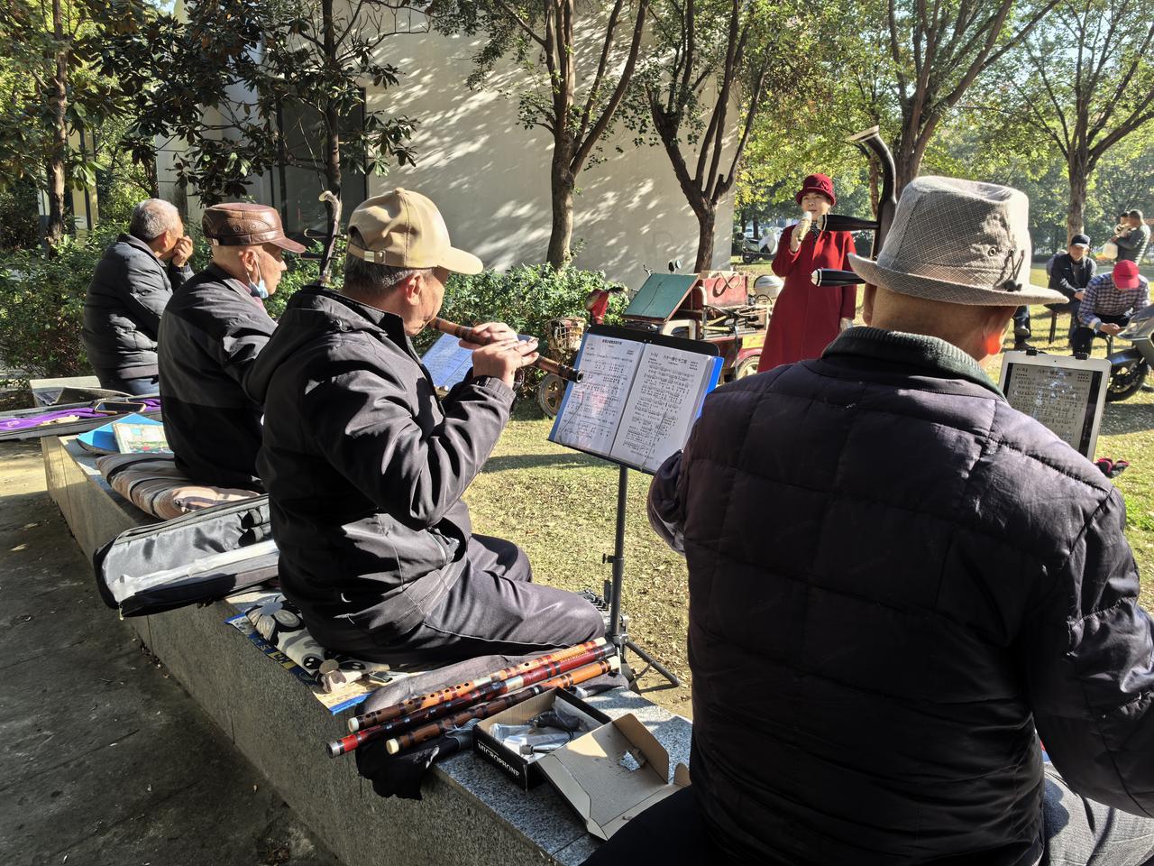 西湾社区的小公园，一群退休的大爷大妈在这里晨练。唱歌、跳舞、打打小麻将等，他