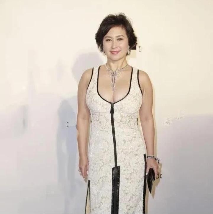 何超琼64岁这状态真的太好了！白色蕾丝无袖长裙配黑色深V拉链，双侧高开叉设