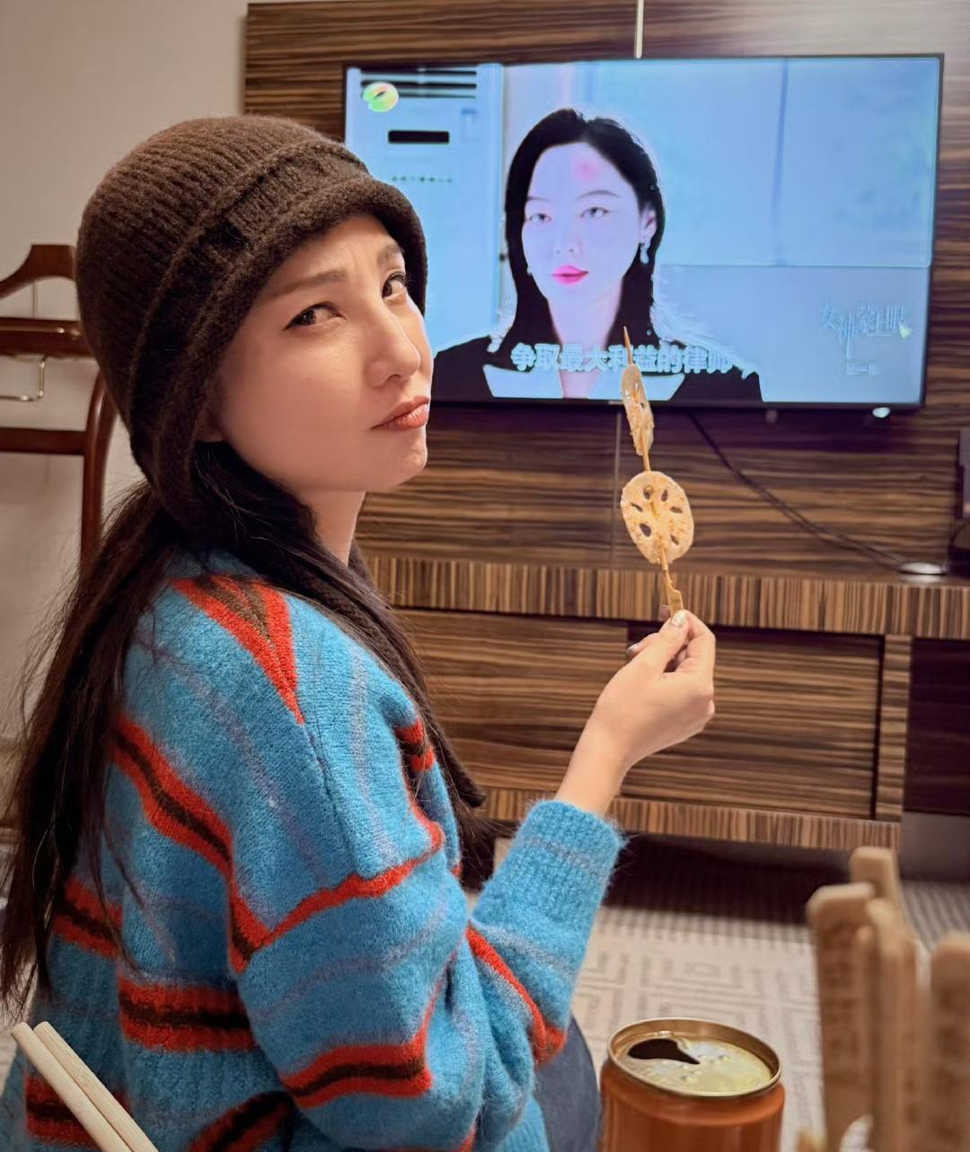 大美女郑希怡，穿着毛衣，戴着毛线帽，拿着藕片，在追剧《女神蒙上眼》……穿