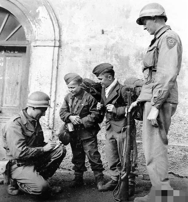 1945年美军俘虏的德军有张照片，两名美宪兵微笑“审问”着两名德军少年兵，这俩娃