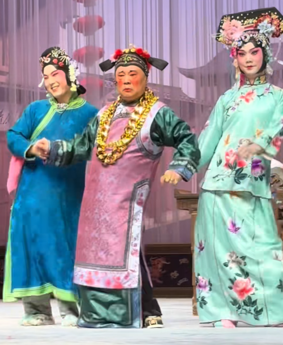 郭德纲画着大红脸蛋，穿着女式长褂，脖子上还缠着好几圈大金链子，在舞台上随着鼓点扭