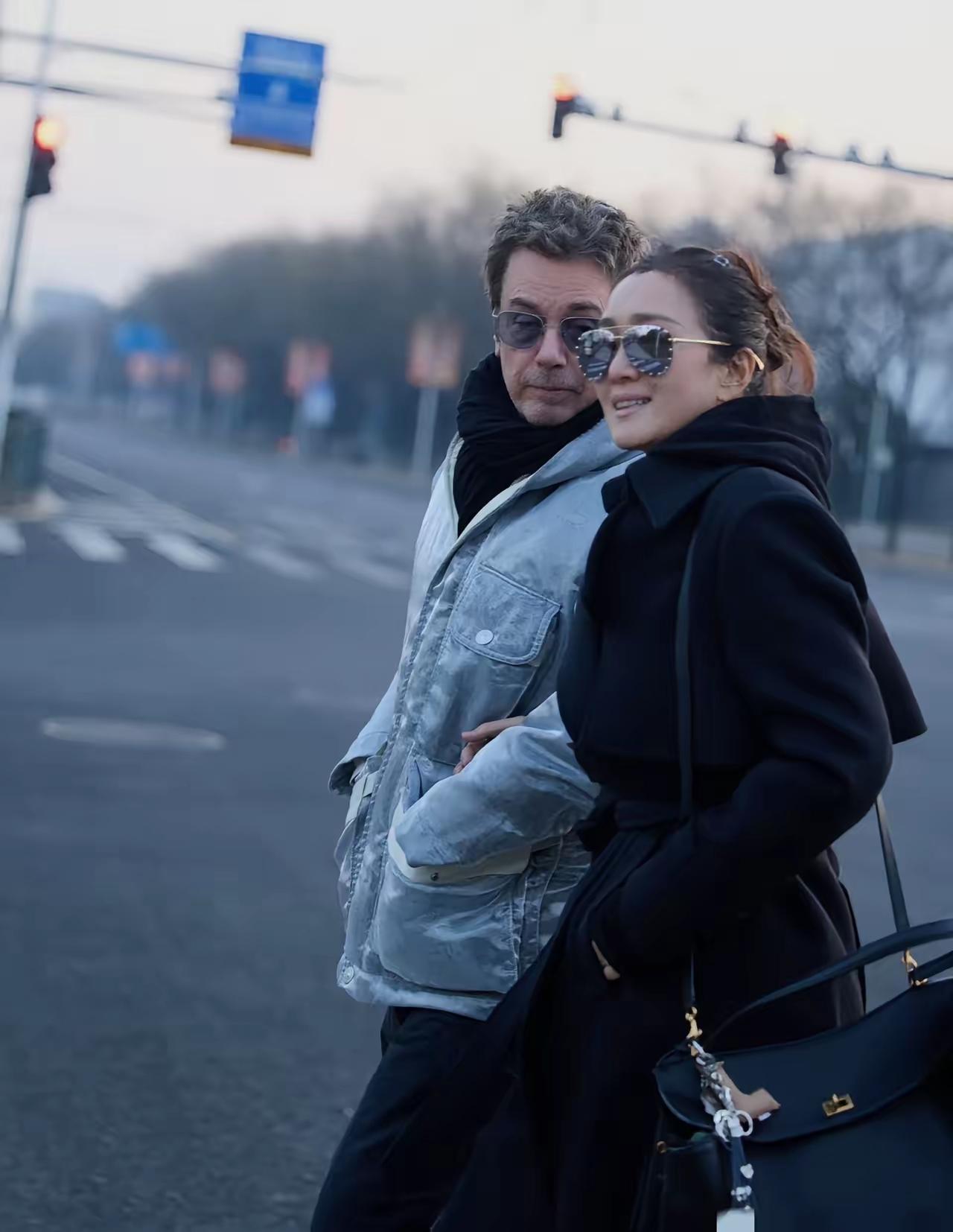 巩俐在北京被拍的照片里，和老公并肩走着，俩人手牵着手，步子慢悠悠的。那法国老公看