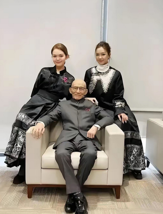 游本昌和两个孙女合照，他已经91岁了，一身黑色西装，精气神十分不错，两个孙女出落