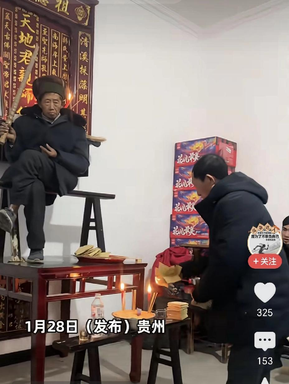 这是啥习俗？活人手拿一金锏坐在桌子上，下面还有人在烧纸，旁边还坐着一群人。这