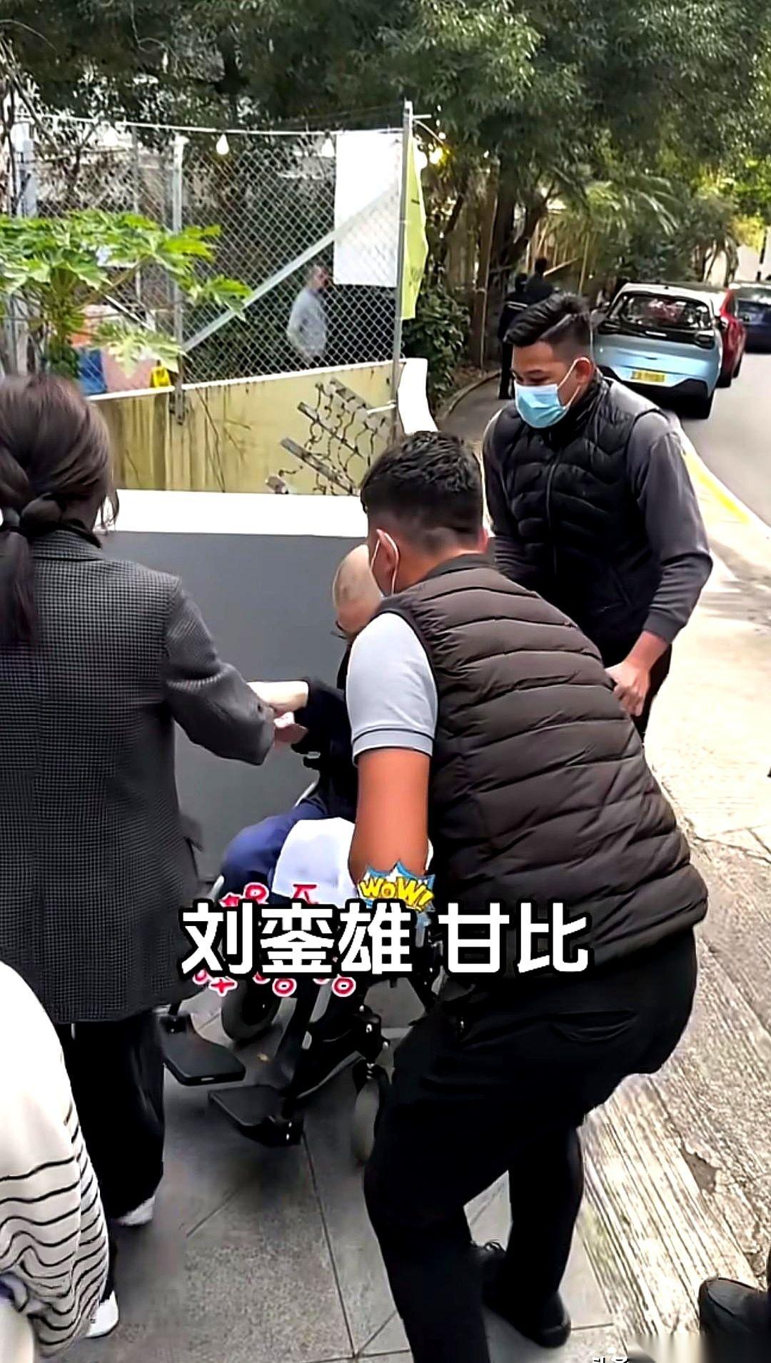 甘比弯腰想用手去掰轮椅那个踏板，刘銮雄立马伸手制止。紧接着，一个眼神过去，旁边