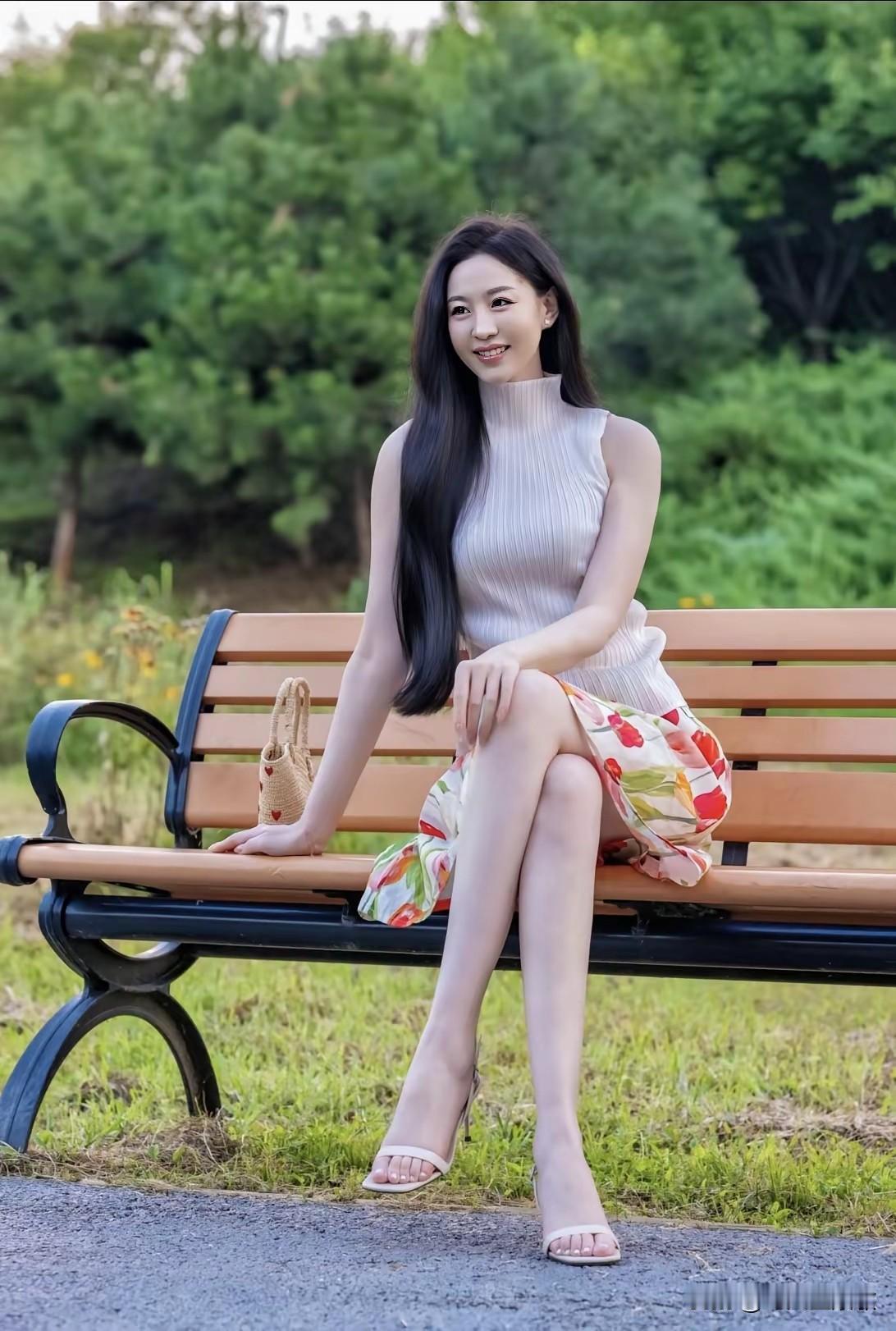 美女坐在公园长椅上，笑容甜美。