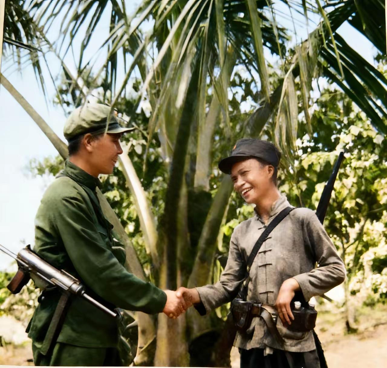 1950年春，解放军渡海解放海南岛，登岛战士与当地游击队琼崖纵队队员握手的场景，