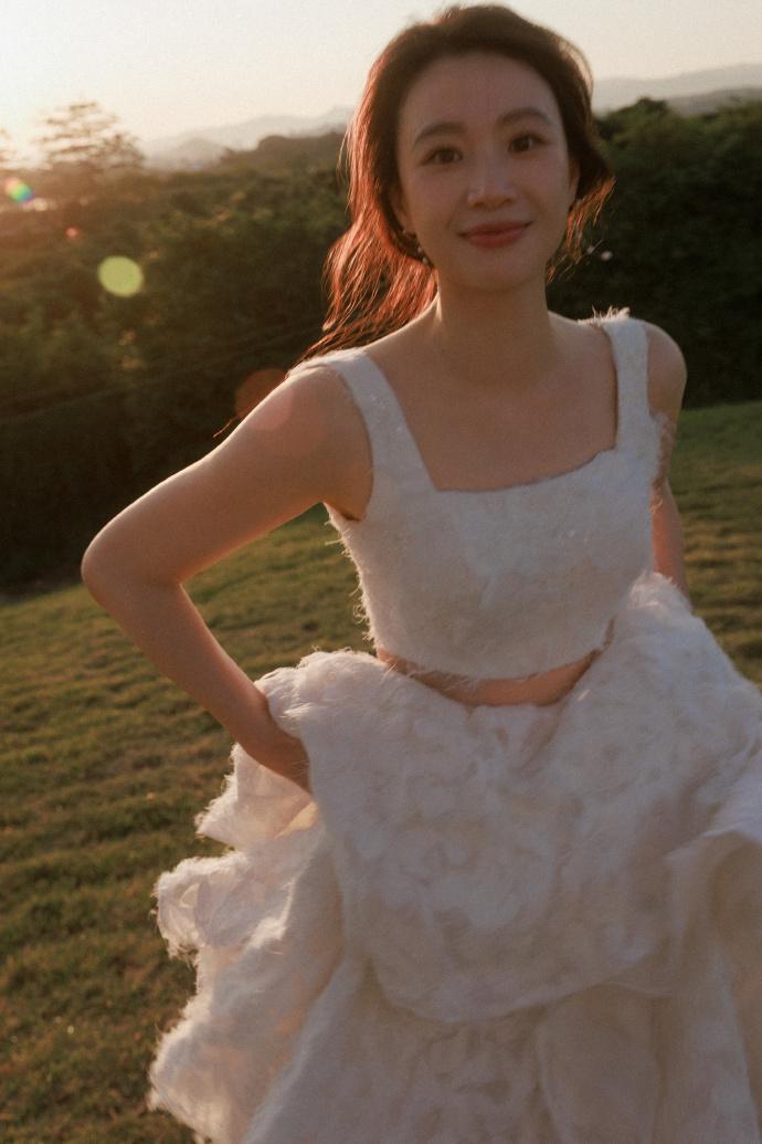 今天李梦拍摄了一组很美的生日大片，她穿着白色的礼服在绿意盎然的自然中行走，确实是