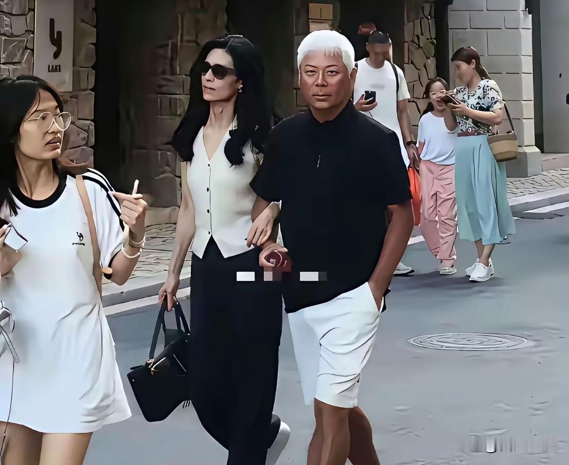 近70岁巫启贤携妻子出游，妻子气质出众，简约穿搭尽显高级感。镜头下，巫启贤一身黑