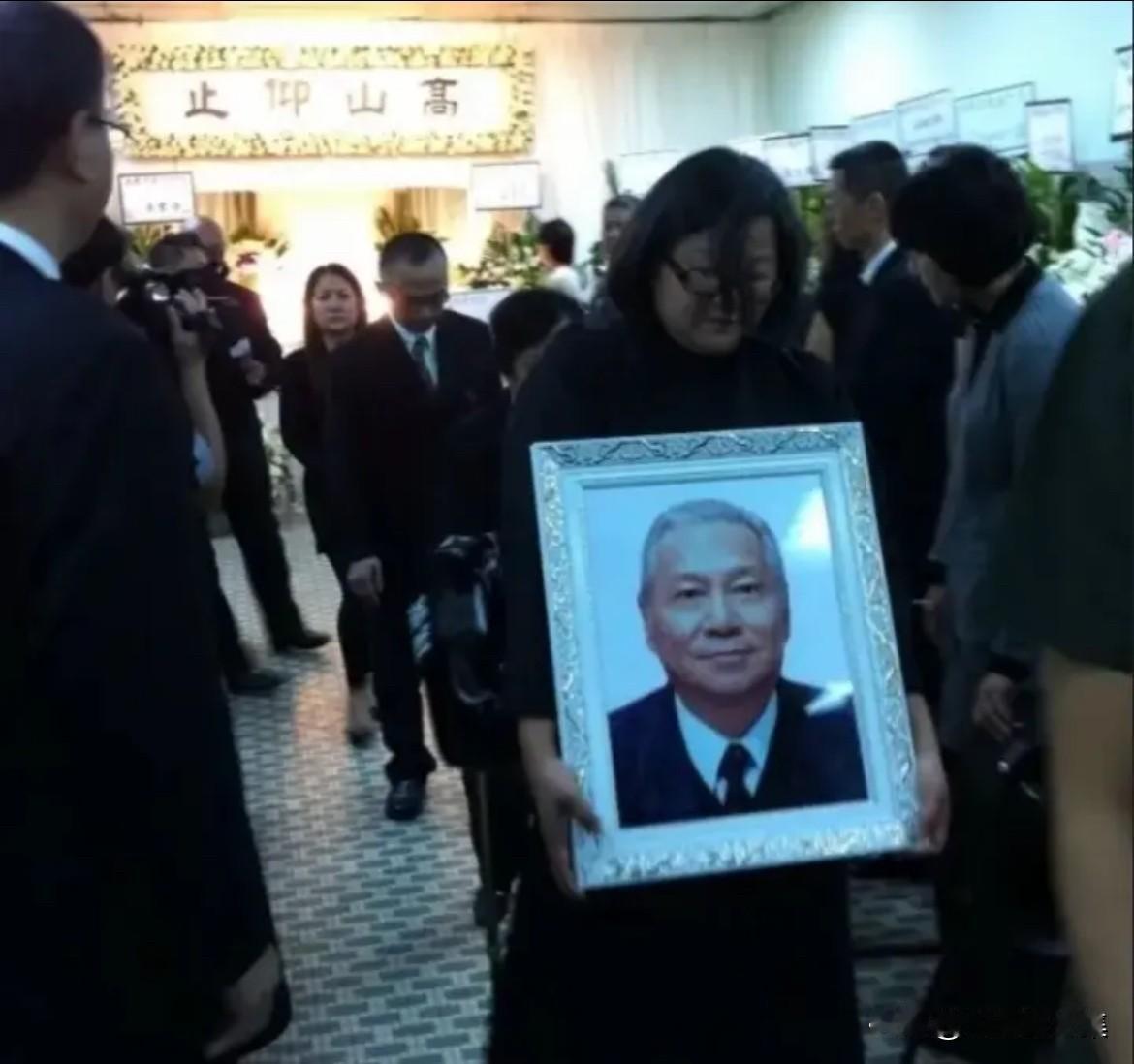 2012年9月8日，洪君彦的追悼会在香港举行，图为洪晃抱着父亲遗像出殡时的一幕。