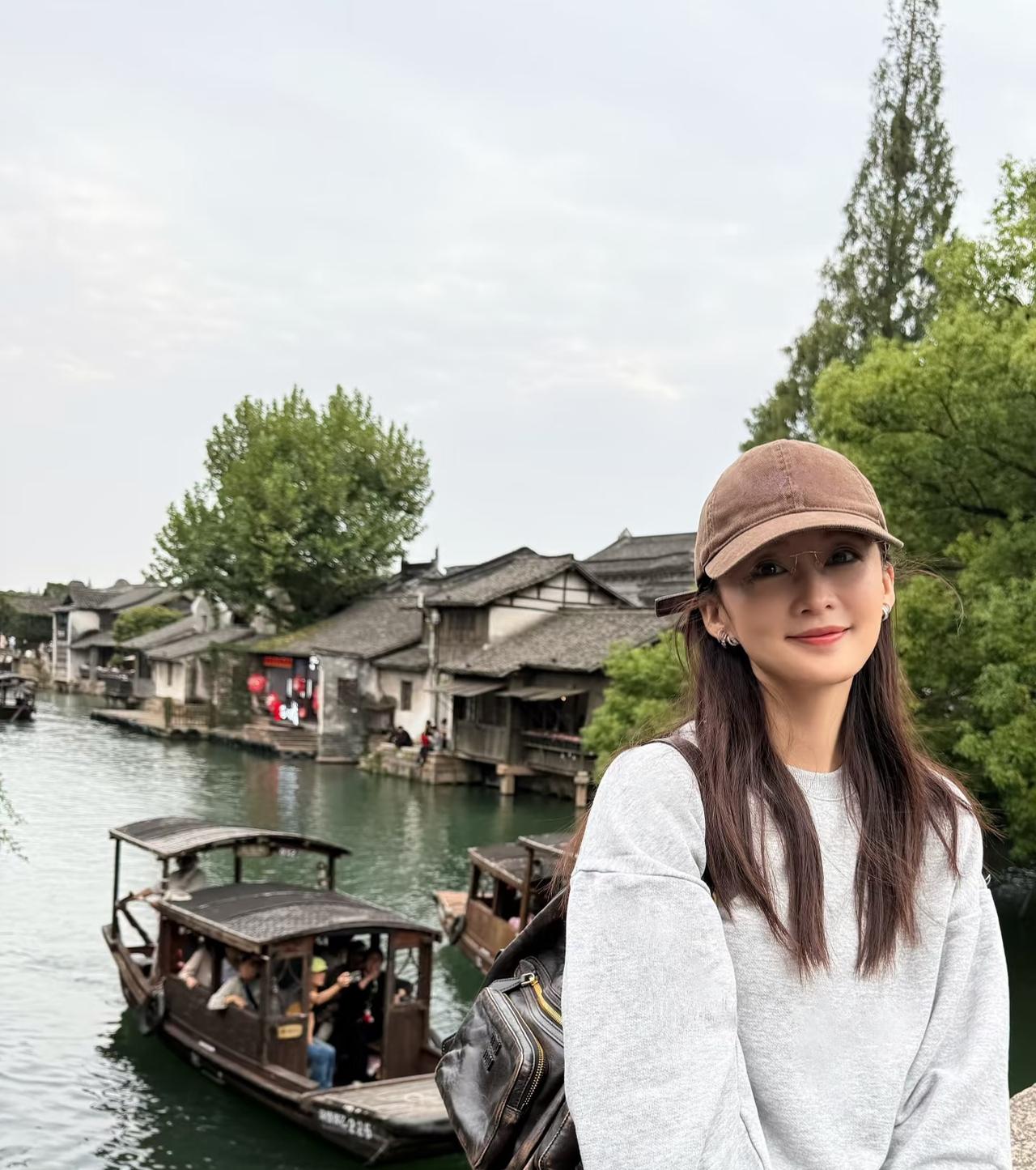 李沁漫游乌镇，浅灰色运动套装配咖色棒球帽，戴金属框眼镜，温柔可人，又美又