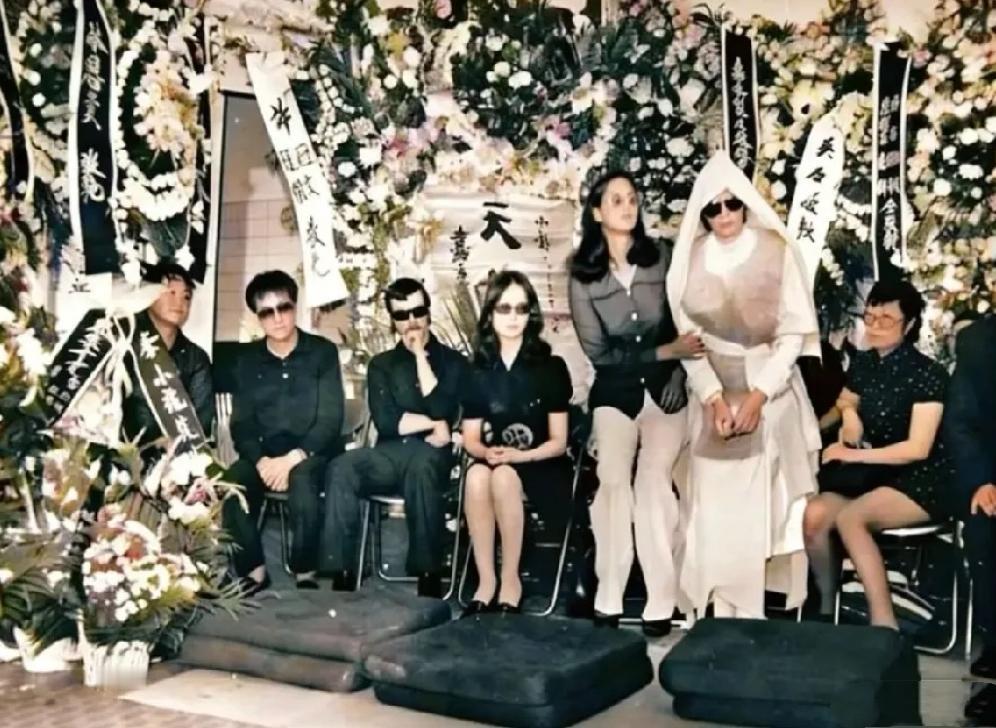 1973年，李小龙葬礼上的一张老照片，葬礼上摆满了花圈，披麻戴孝由人搀扶着的是妻