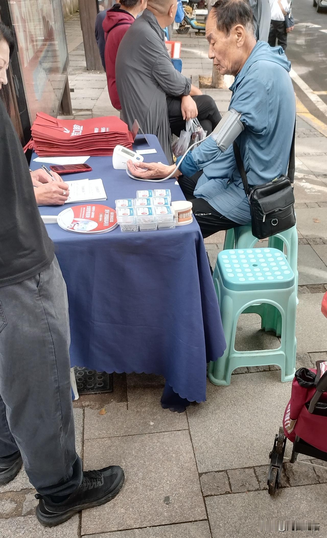 图中这位大爷，听到免费量血压，大热天二十五六度，刚走过来脸还红着，坐下就量。我