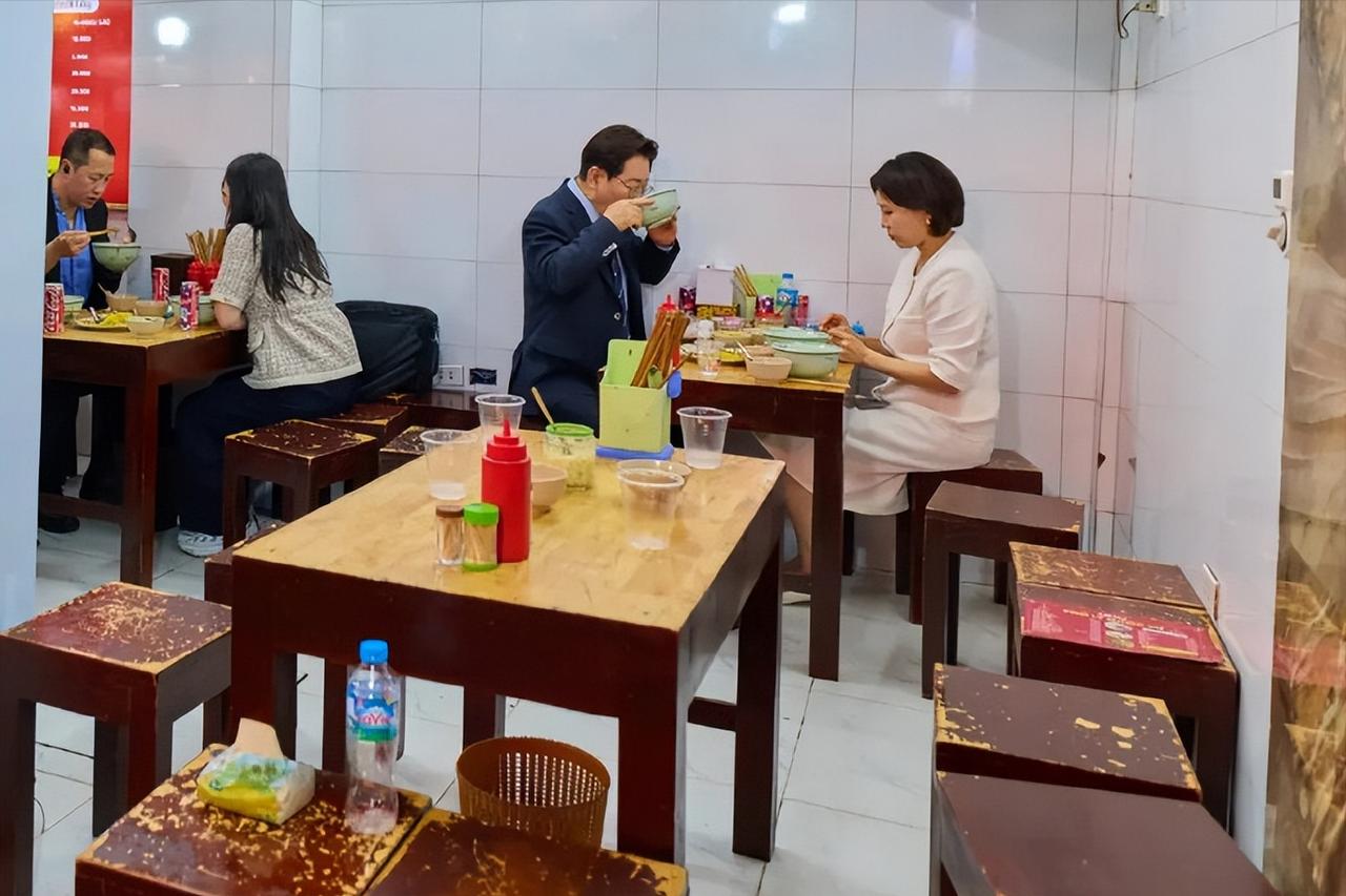 李在明在越南逛街太松弛接地气了，吃饭端着碗喝，另外这家小饭店内凳子都掉漆了。4