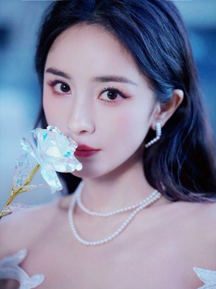 杨幂轻捧花束，花团锦簇间绽放出她的身影。灿烂的花朵在她手中更显含蓄，却比不上她眉