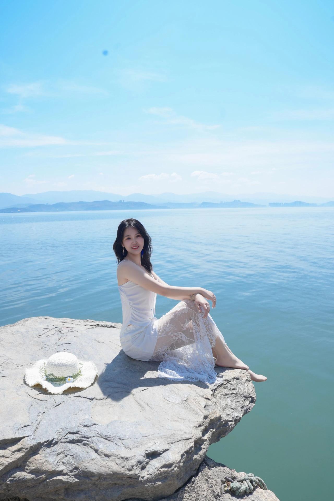真心话茶局湖光潋滟处，白裙少女倚石而坐，享受阳光与海风。