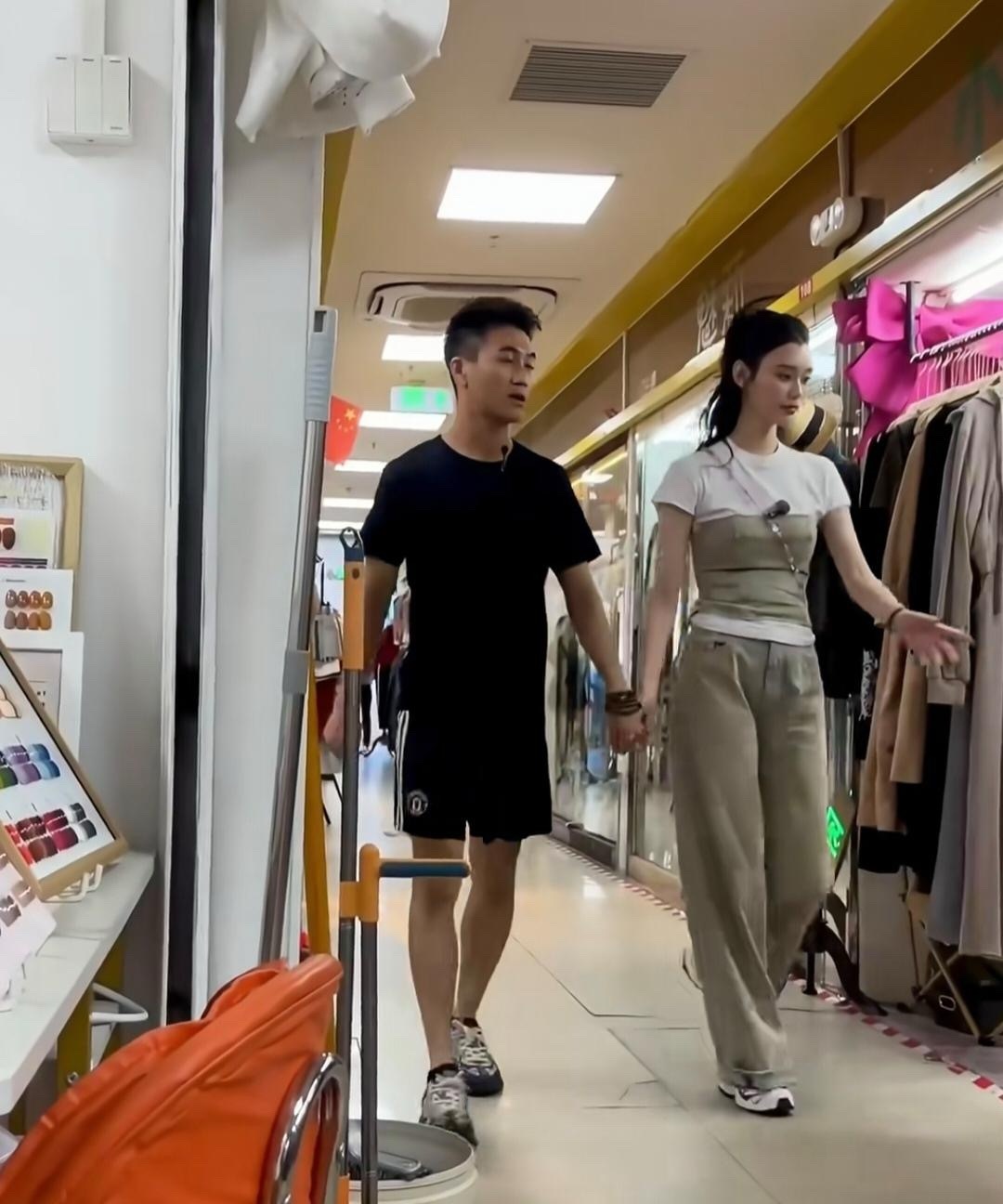 奚梦瑶和老公何猷君一起逛平价服装店，两个人手牵手，个子看起来一样高。他们穿衣打扮
