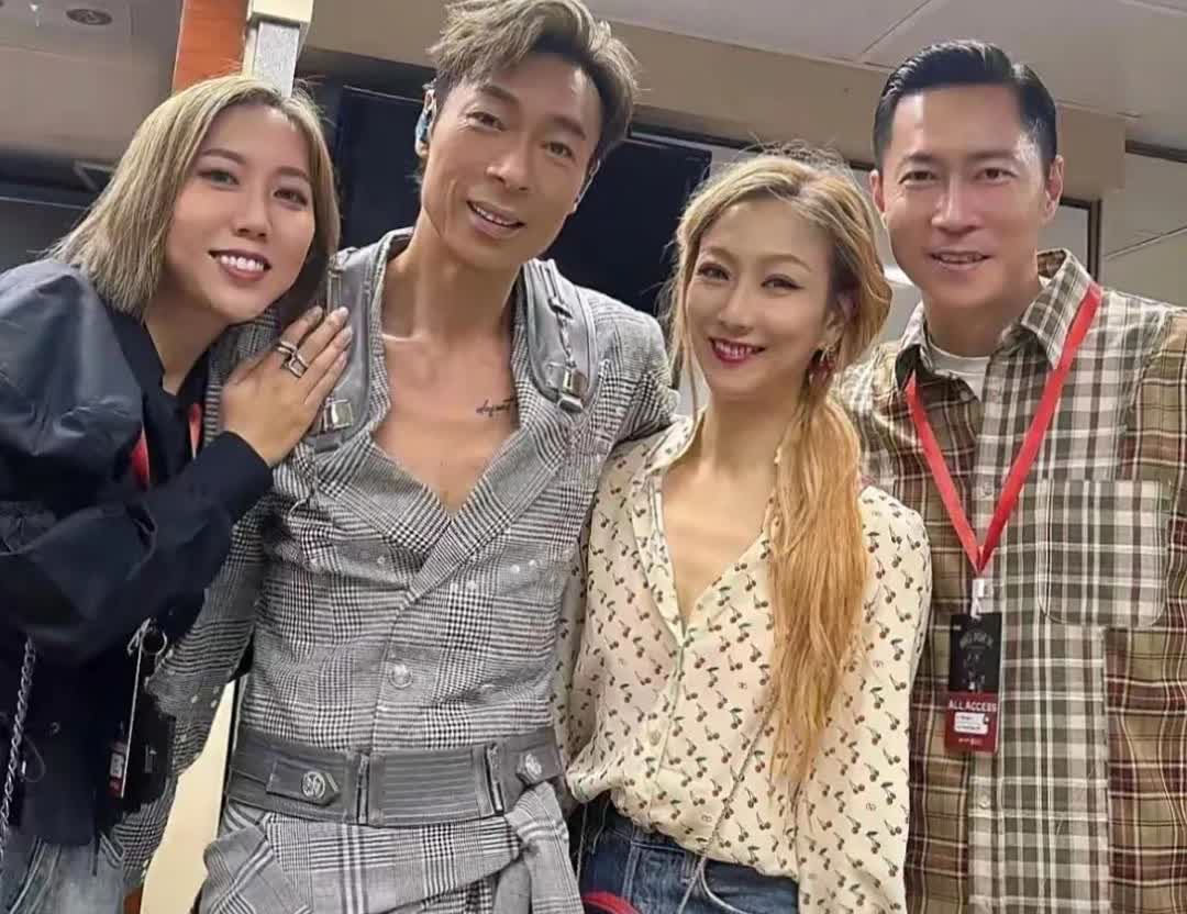 画面中穿一身另类格子装的许志安肤黑脸长，背微驼，褶满脸，纹身抢镜；一头金发的郑秀