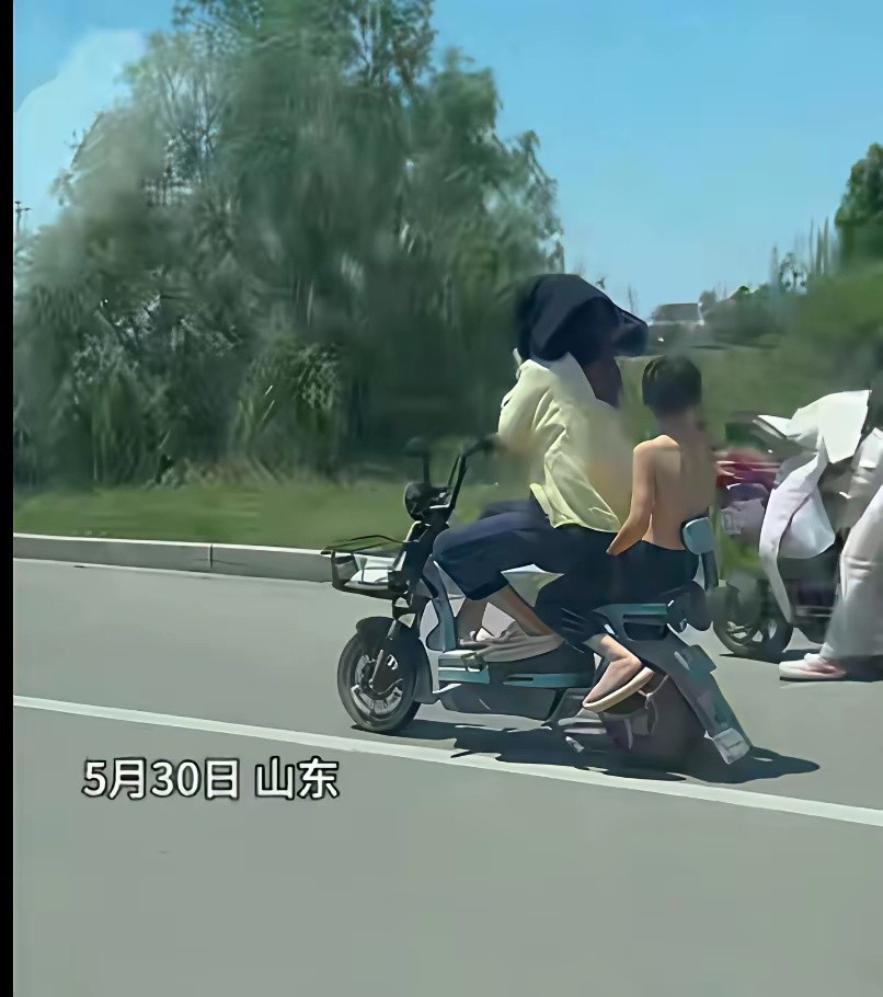 绝对亲生的！5月30日，山东，妈妈骑着电动车带着儿子，因为太阳大，妈妈怕晒，要儿