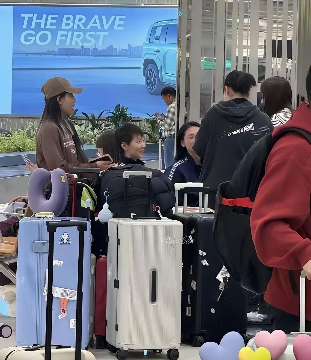 国乒大部队落地新加坡后，大家都在等行李。只见剪短了头发的曼昱一脸笑容地和围着她