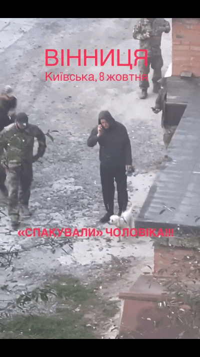 乌克兰文尼察，一名成年男子在街道上边遛狗边接打电话，根本没有在意旁边围上来多名征