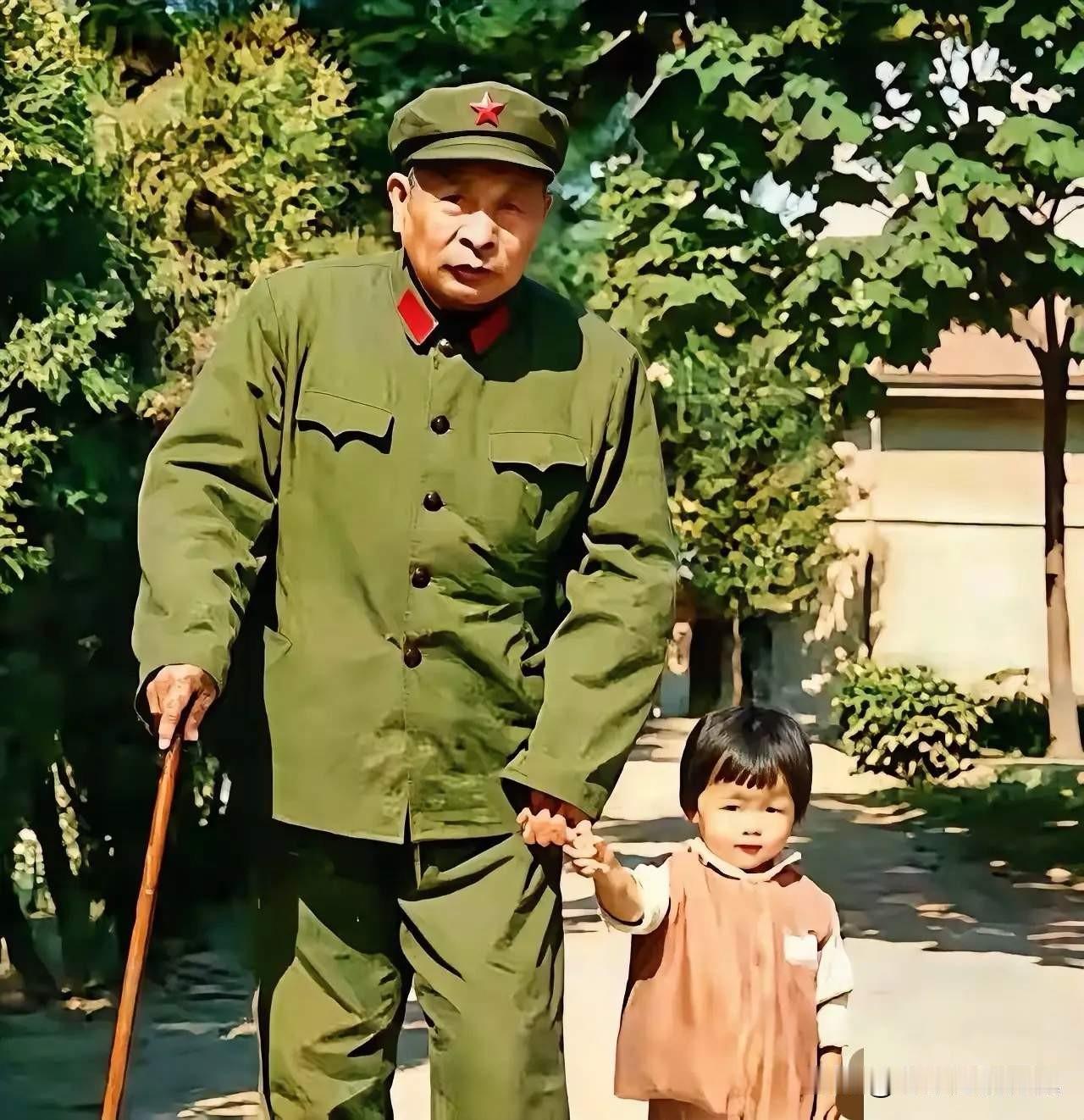 这张温情老照片，记录了钟期光上将牵着年幼孙女蓝柯散步的瞬间。一身军装的老将军手
